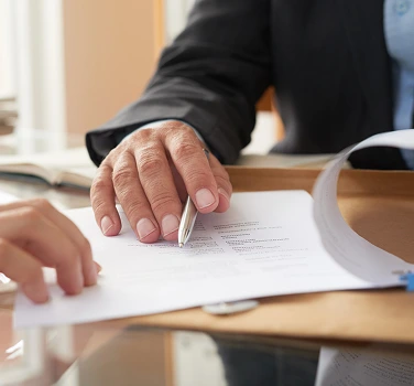 Close-up of business professionals reviewing compliance documents and managing paperwork for audit preparation