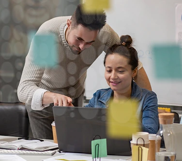 Team members collaborating on CRM and job tracking software updates at a desk with sticky notes on glass