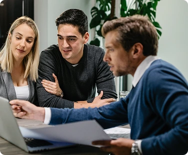 Business meeting with agent and clients reviewing insurance certificate requests and renewal documents on a laptop