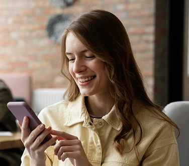 Smiling young woman using her smartphone to manage appointments and communicate with customers for scheduling support